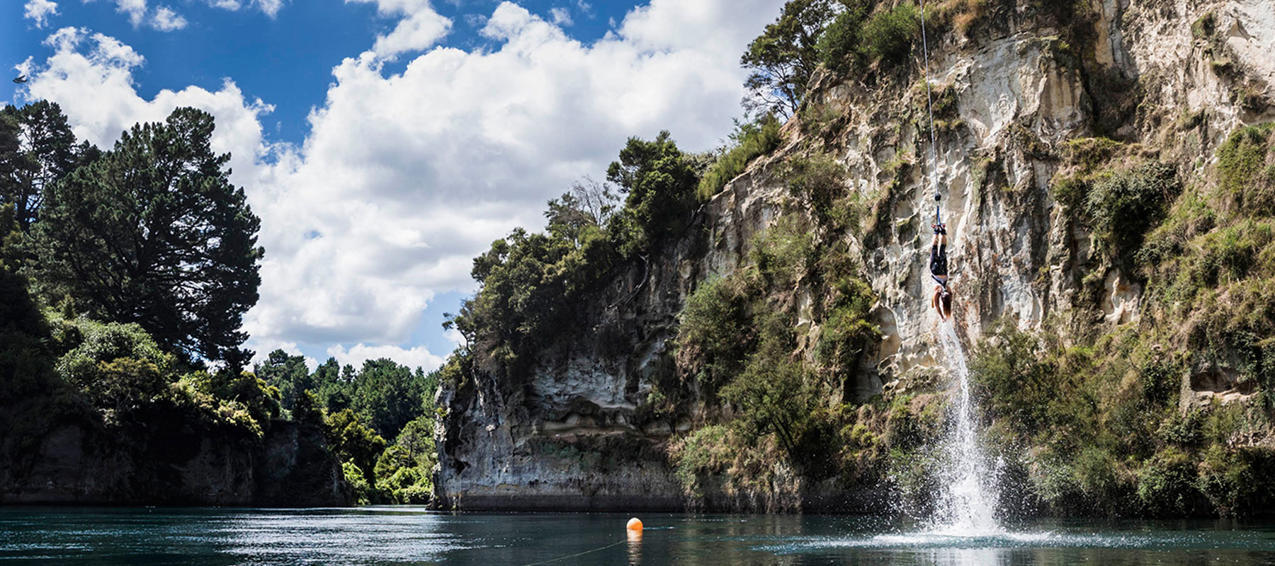 Person mid-air bungy jumping into calm water below at AJ Hackett Bungy in Taupō, New Zealand.